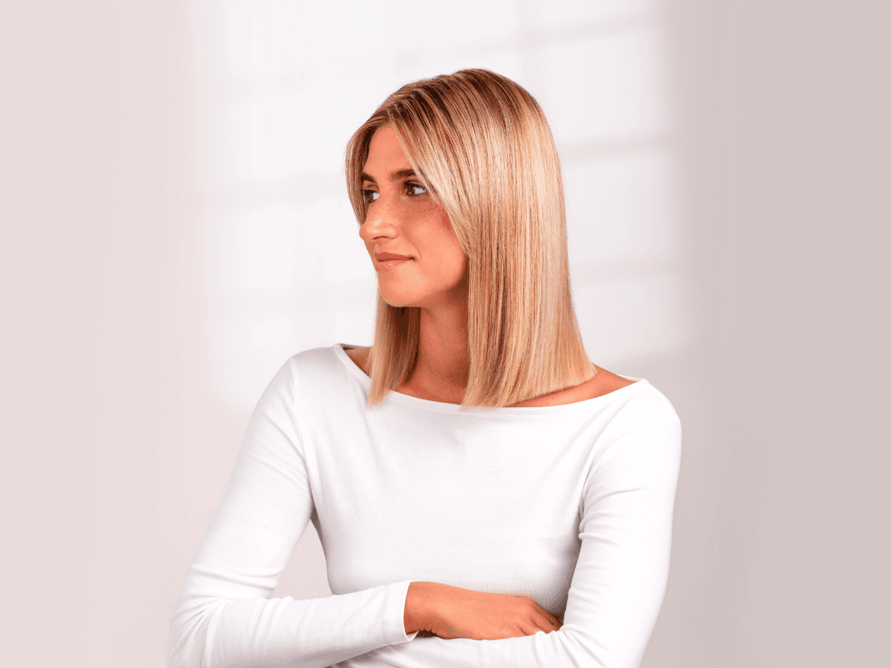 Portrait d'une femme aux cheveux blonds mi-longs, parfaitement lisses et lumineux, mettant en avant un résultat d'un soin botox capillaire.