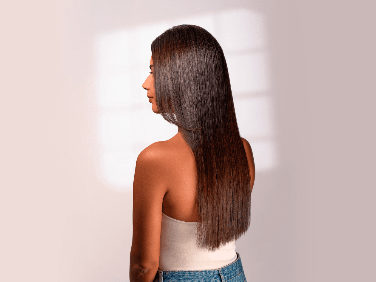 Portrait de profil d'une femme brune aux cheveux longs et ondulés, mettant en avant la brillance, la vitalité et la douceur de sa chevelure suite à un soin Botox capillaire.