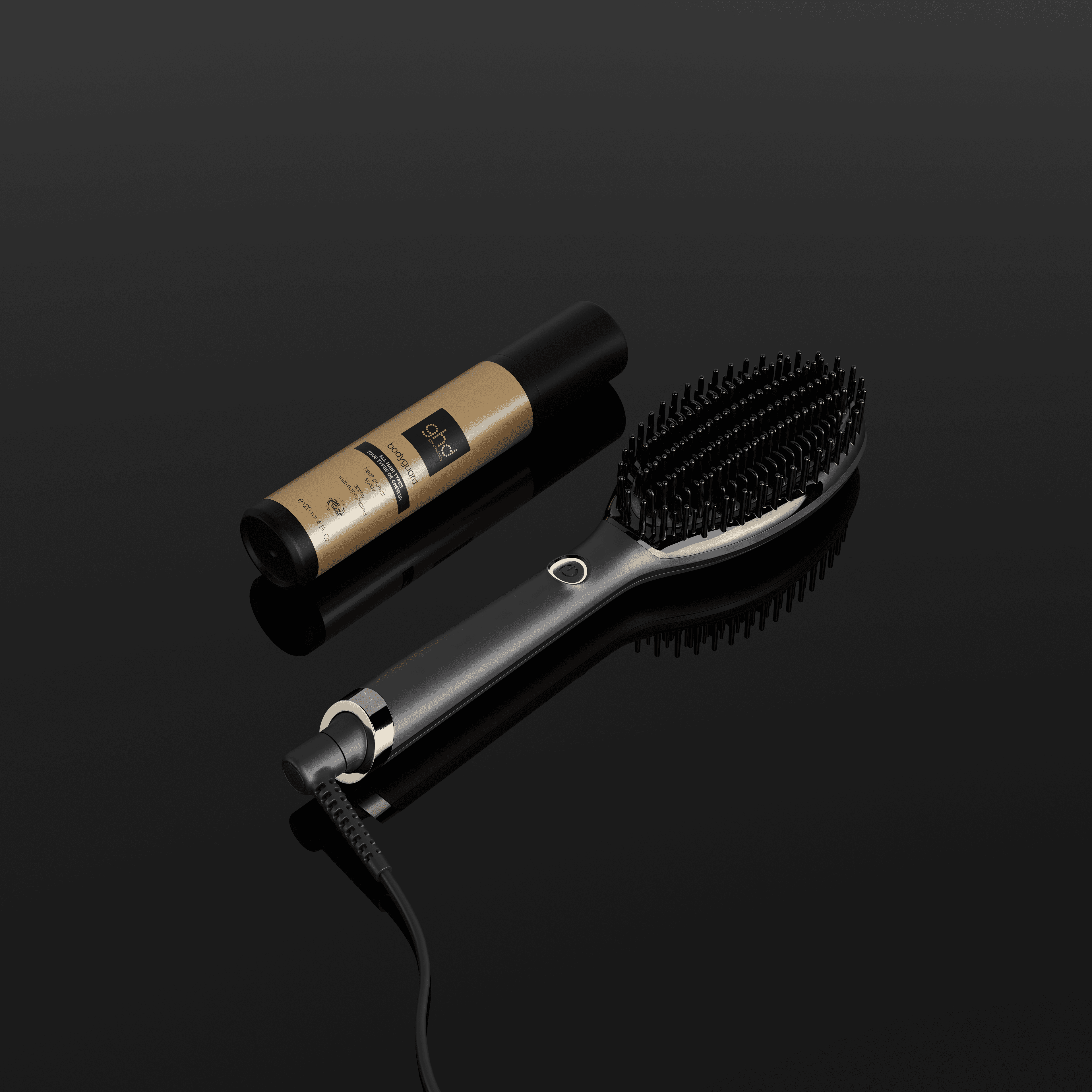 Sur un fond noir, brosse ghd glide+ posée par terre à côté du protecteur thermique ghd.